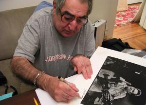 Jim Marshall signs his iconic Johnny Cash print for Brad Mangin in his San Francisco home on February 11, 2009. (Photo by Grover Sanschagrin)